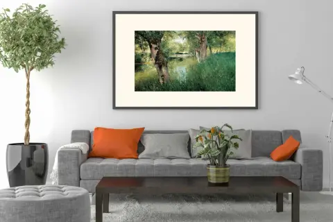 A modern impressionism painting of a serene riverbank with lush green grass and trees, framed above a grey sofa with orange and grey cushions.