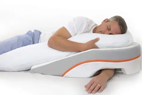 Man sleeping on his left side, using a wedge pillow designed to help with reflux.