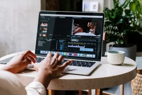 Montażysta filmów pracuje nad projektem na laptopie. Zastanawiasz się, ile zarabia montażysta filmów?