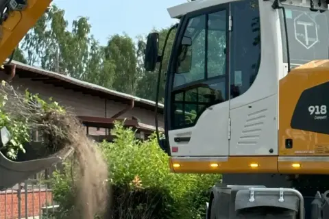Grävmaskin tömmer jord och grenar. Marken är lerig, perfekt för att bygga på silt.
