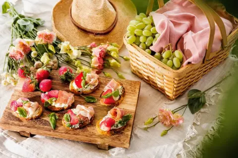 En härlig picknick med bruschetta, jordgubbar, vindruvor i korg och en stråhatt. Perfekt picknick mat för en solig dag.