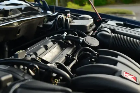 Gros plan sur le moteur d'une voiture, avec le bouchon du voyant d'huile moteur visible.