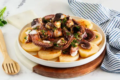 Piatto di polpo alla gallega, con tentacoli succulenti su patate affettate, condito con paprika e prezzemolo fresco.