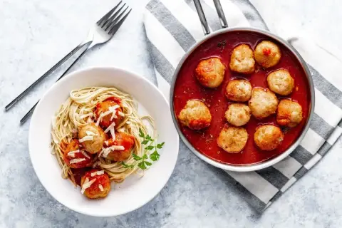 Pulpety Ani Gotuje w sosie pomidorowym z makaronem spaghetti i parmezanem. Pyszne danie gotowe do podania.