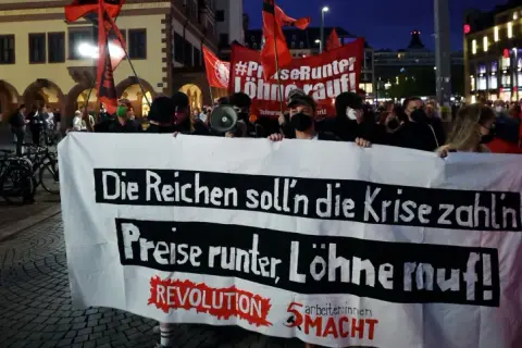 Demonstranten mit Banner "Die Reichen soll'n die Krise zahlen, Preise runter, Löhne rauf!" zeigen die politische polarisierung definition.