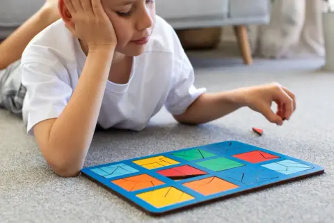 Chłopiec z ADHD układa kolorowe klocki na dywanie. To świetne zabawy dla dzieci z ADHD, rozwijające koncentrację i zdolności manualne.