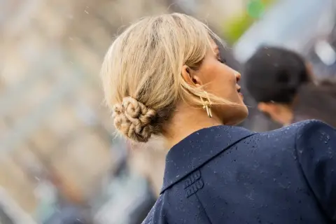 Chignon facile e intrecciato, con orecchini dorati a forma di croce.