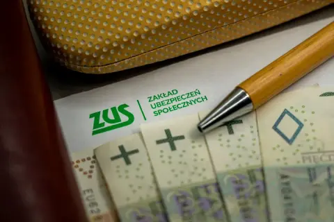 Zwolnienie z ZUS? Na papierze z logo ZUS leżą polskie banknoty i długopis.