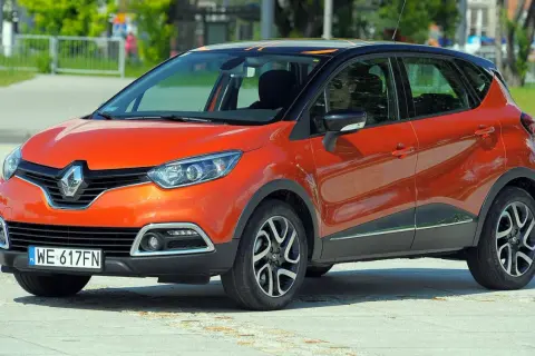Pomarańczowy Renault Captur 2015 z czarnym dachem i pomarańczowymi akcentami stoi na placu.