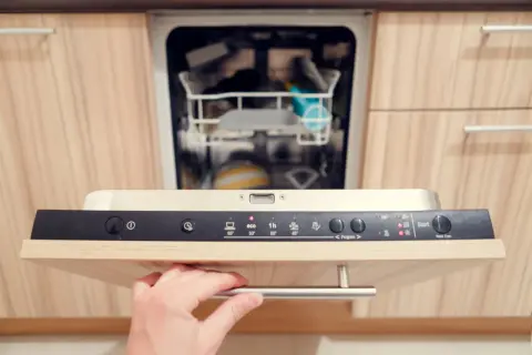 Hand öffnet Spülmaschine. Aquastop entblocken ist hier kein Thema, da die Maschine bereit für ein neues Programm ist.