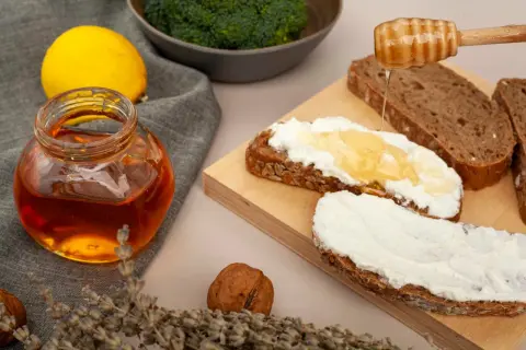 Słoik miodu, cytryna, brokuły i chleb z serkiem i miodem. Czy miód jest zdrowy? Tak, zwłaszcza gdy jest naturalny i spożywany z umiarem.