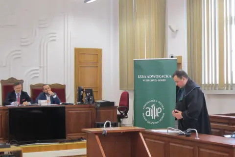 Sąd w Zielonej Górze: dwaj mężczyźni w togach siedzą za stołem, jeden w todze stoi obok.