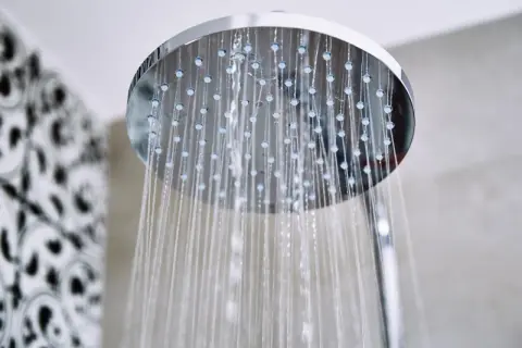 Acqua che scorre da un soffione doccia moderno, un promemoria per sapere come pulire il soffione della doccia per un getto perfetto.