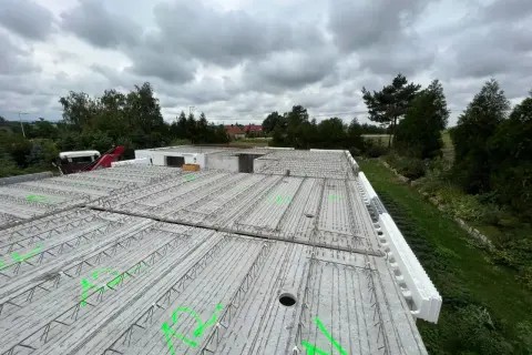 Gotowy do zalania strop filigran, z zielonymi oznaczeniami i widocznym szalunkiem traconym.