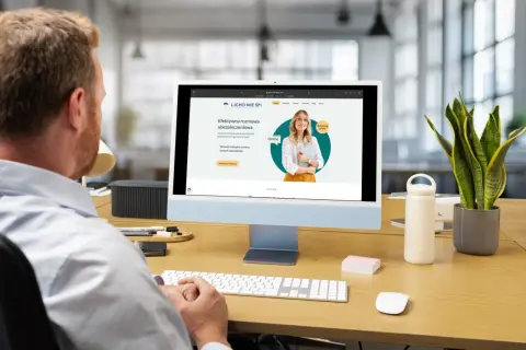 Mężczyzna pracuje przy komputerze, na ekranie którego widoczna jest strona internetowa z rankingiem agentów ubezpieczeniowych.