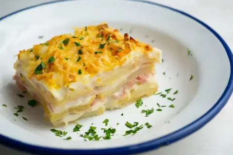 Pyszny kawałek zapiekanki ziemniaczanej z szynką i serem, idealny na obiad. Ten przepis na lasagne ziemniaczaną zachwyci każdego!