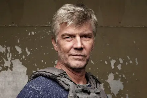 Johan Falk i ny film. En man med grått hår och väst ser allvarlig ut.