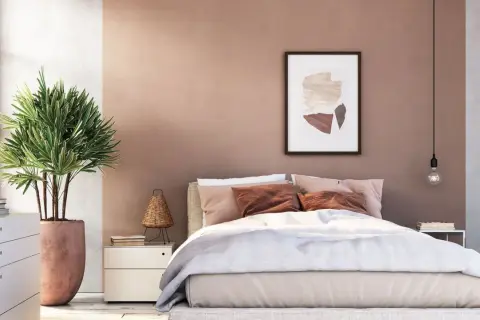Gemütliches Schlafzimmer mit sanfter, rosafarbener Wandfarbe. Ein großes Bett mit beiger Bettwäsche und braunen Kissen lädt zum Entspannen ein.