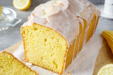 Saftiger Zitronenkuchen mit Zuckerguss, perfekt für Ihr nächstes zitronenkuchen rezept. Ein Stück ist bereits angeschnitten.