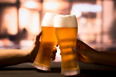 Due mani brindano con due bicchieri di birra ghiacciata, un momento di piacere che celebra la birra proprietà.