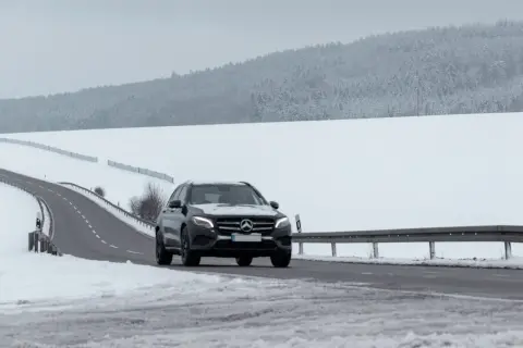 Czarny Mercedes GLE jedzie po ośnieżonej drodze. Jego wymiary pozwalają na pewne poruszanie się w trudnych warunkach.