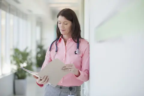 Médecin consultant un dossier, peut-être pour un deuxième avis médical et son remboursement.