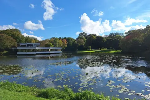 Ein moderner Bau am Ufer eines Teichs mit Seerosen, umgeben von Bäumen. Ein friedlicher Ort, der zeigt, was man in Bremen gesehen haben muss.