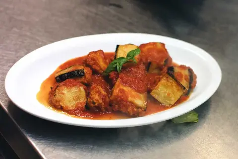 Friterad aubergine i tomatsås, toppad med färsk basilika. En läcker italiensk rätt.