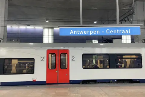 Pociągiem po Europie: biały wagon z czerwonymi drzwiami na stacji Antwerpen - Centraal. W oknach widać pasażerów.
