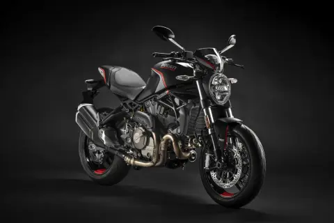 Czarny motocykl Ducati Monster na ciemnym tle.