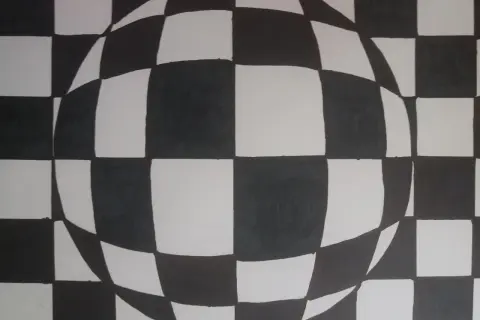 Iluzja 3D w stylu op art. Czarno-biała szachownica zakrzywia się, tworząc wrażenie kuli.