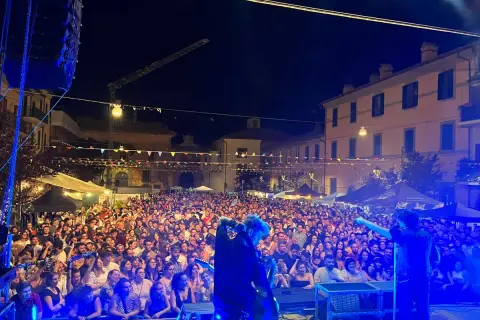 Folla immensa a una festa del luppolo, con musicisti sul palco che intrattengono il pubblico sotto un cielo stellato.