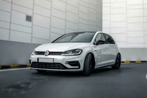 Vit Volkswagen Golf R, en bil som kan drabbas av 1.4 TSI-problem, kör på en asfalterad väg.
