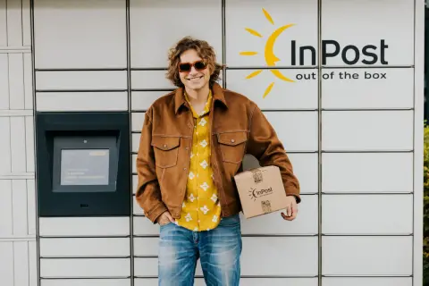 Uśmiechnięty mężczyzna z paczką InPost. Wysłał ją w piątek, więc pewnie dojdzie w poniedziałek.
