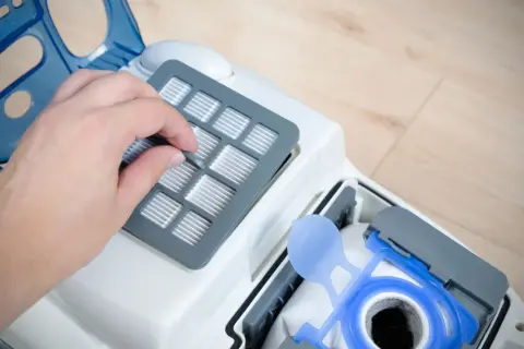 Dłoń wymienia filtr w odkurzaczu. To ważny element, czy to filtr EPA, czy HEPA, zapewnia czyste powietrze.