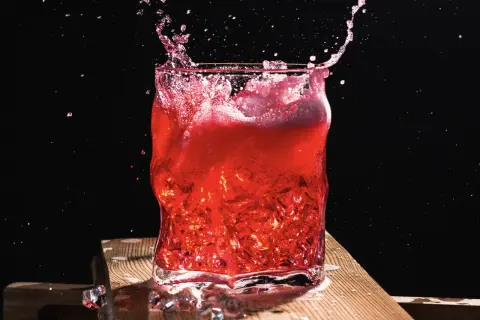 Intensywny drink z wiśniówką w szkle, z rozpryskującym się płynem i lodem.