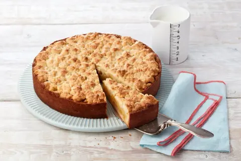 Ein goldbrauner Apfelkuchen mit Streuseln, ein Stück wird gerade herausgehoben. Sieht aus wie Omas Apfelkuchen!