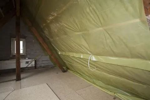 Podczas ocieplania poddasza, odpowiednia folia pod wełnę mineralną na strop zapobiega zawilgoceniu. Widoczna żółta folia paroprzepuszczalna chroni izolację.