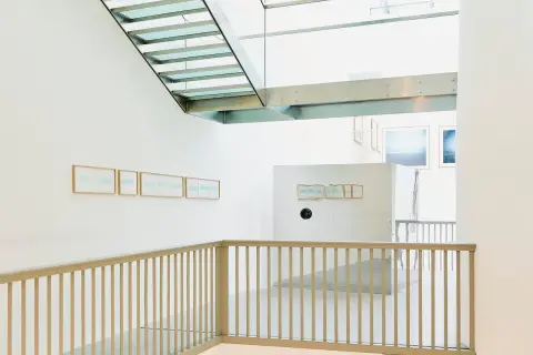 Interno moderno con scale in vetro e metallo. Opere di Christian Martinelli appese alle pareti bianche.