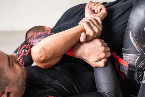 Två män brottas på en matta. En av dem har en omoplata bjj-position.