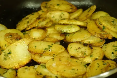 Patatas panaderas al horno crujientes, doradas y con perejil picado, listas para disfrutar.