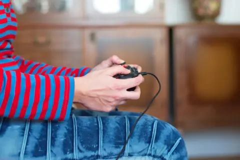 Ręce trzymające kontroler, gotowe do gry. Dowiedz się, jak podłączyć Nintendo do TV i rozpocząć przygodę!