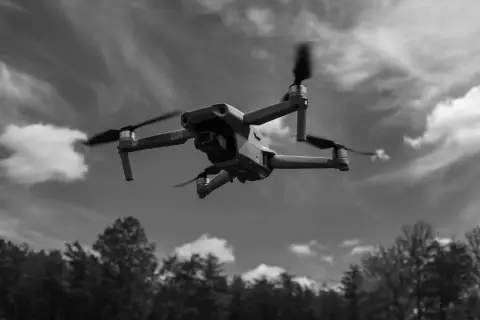 Un drone survole une forêt sous un ciel nuageux.