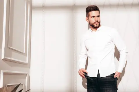 Mężczyzna w białej koszuli i jeansach, prezentujący styl slim fit.