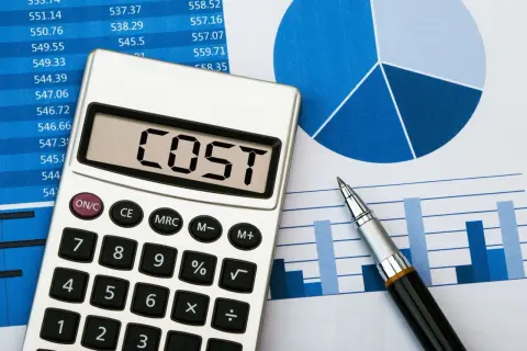 Kalkulator z napisem "COST" na tle wykresów i tabel, symbolizujący analizę i redukcję kosztów.