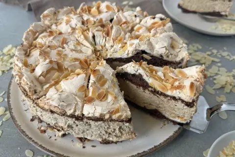 Eine himmelstorte mit kirschen, verziert mit Mandelblättchen, wartet darauf, angeschnitten zu werden.
