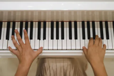 Dziecko ćwiczy grę na pianinie. Ręce na klawiszach, początek nauki muzyki.