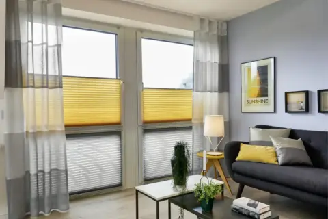 Modernes Wohnzimmer mit stilvoller Kombination aus gelben Wabenplissees und transparenten Gardinen.