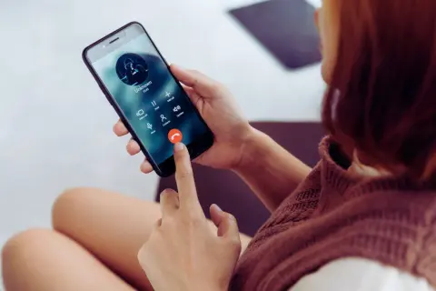 Kobieta trzyma telefon, na ekranie połączenie od nieznanego numeru. Zastanawiasz się, jak sprawdzić, czy telefon jest na podsłuchu?