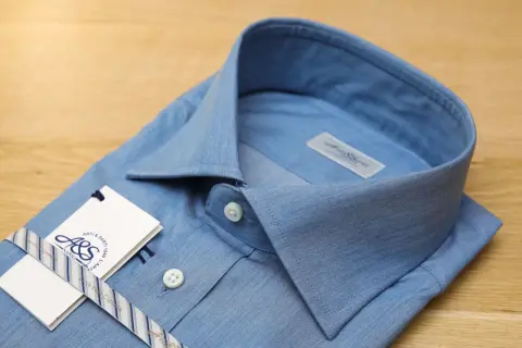 Camicia azzurra con colletto button down, etichetta e nastro a righe.